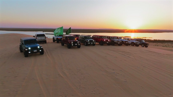 سيارات دفع رباعي على رمال بحيرة الأصفر عند الغروب، لقطة جوية.