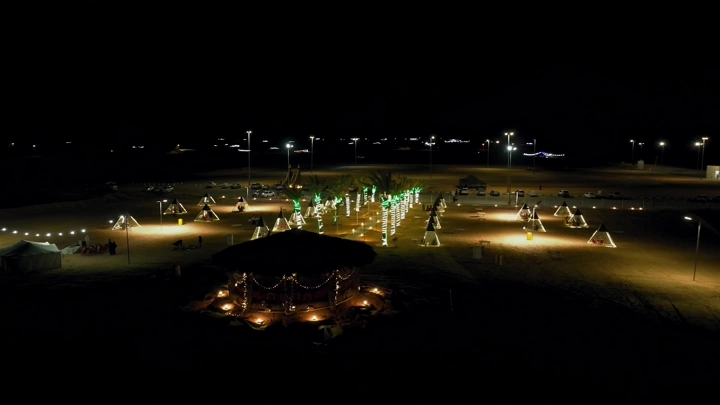 مخيم مضاء ليلاً في حائل مع ظهور البرق، تصوير جوي.