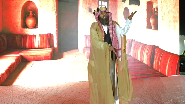 رجل كبير بالسن يرتدي زي تقليدي في غرفة عربية، لقطة داخلية.