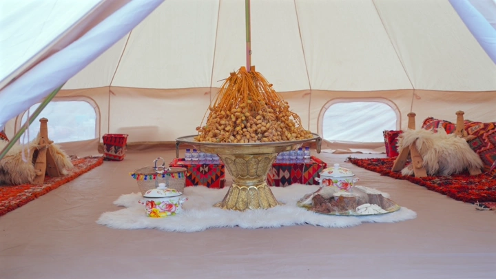 خيمة تقليدية مع ضيافة وتمر في المنتصف، لقطة داخلية.