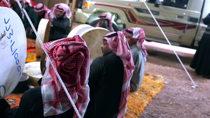 رجال يرتدون الزي التقليدي يعزفون على الطبول في الهواء الطلق، تصوير قريب.