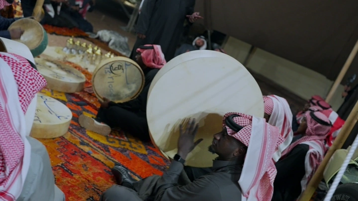 مجموعة رجال تعزف الدفوف في خيمة تقليدية، لقطة داخلية.