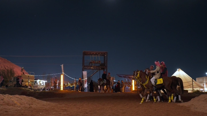 فرسان على خيول في استعراض ليلي، لقطة واسعة.