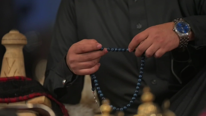 شخص يحمل سبحة زرقاء في يده، لقطة قريبة.