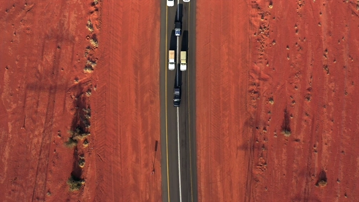 سيارات على طريق وسط أرض زراعية حمراء، لقطة جوية.