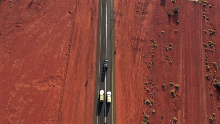 سيارات تسير على طريق في صحراء حمراء، لقطة جوية.