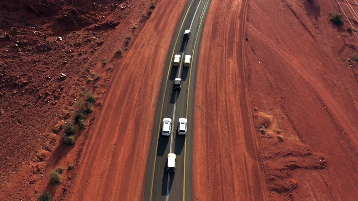 سيارات تسير على طريق بين الجبال الحمراء، لقطة جوية.