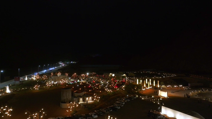 منظر جوي لمقهى مضاء ليلاً مع سيارات متوقفة حوله.