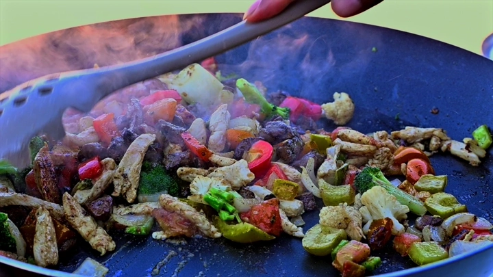 طهي الخضار واللحم في مقلاة على النار، لقطة قريبة.