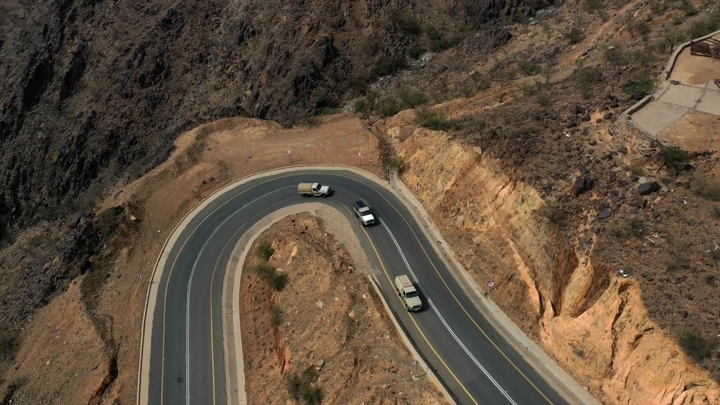 طريق عقبة جبلي متعرج مع سيارات، لقطة جوية.