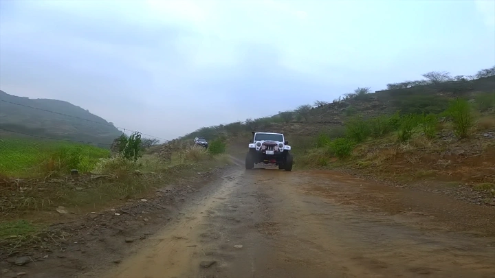 سيارة تسير على طريق موحل في منطقة جبلية، لقطة من الأمام.