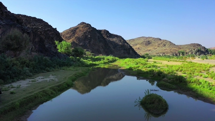 وادي بيشة مع انعكاس الجبال في الماء، لقطة جوية.