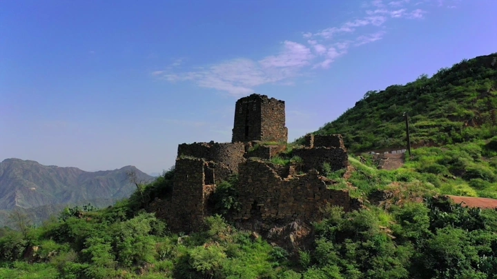 قلعة حجرية في رجال المع تحت سماء زرقاء، لقطة من الجو.