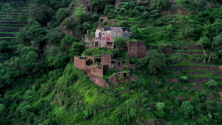 قلعة قديمة محاطة بالخضرة في رجال المع عسير، لقطة جوية.