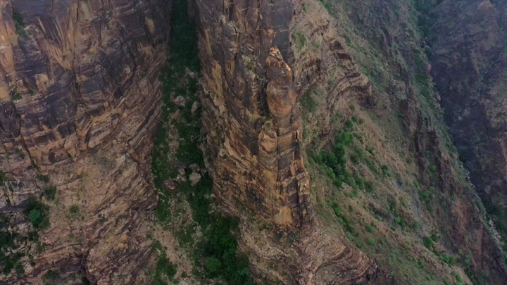 جبال القهر في جازان، لقطة جوية تظهر التضاريس الصخرية والنباتات الخضراء.