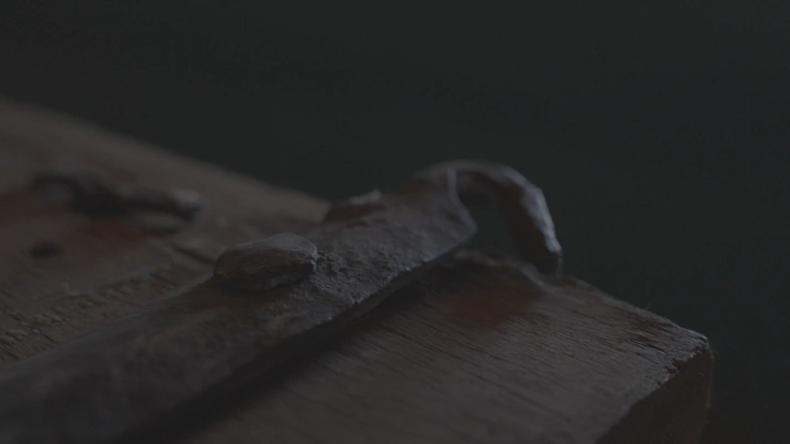 مقبض باب خشبي قديم في إضاءة خافتة، لقطة قريبة.