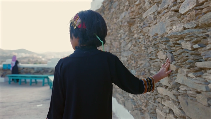 طفلة ترتدي ملابس تقليدية في عسير، لقطة خلفية.