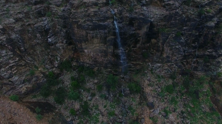 شلال يتدفق من منحدر صخري في عسير، لقطة جوية.