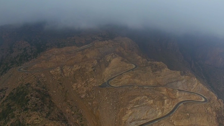 طريق متعرج في جبال السروات تحت الغيوم، لقطة جوية.