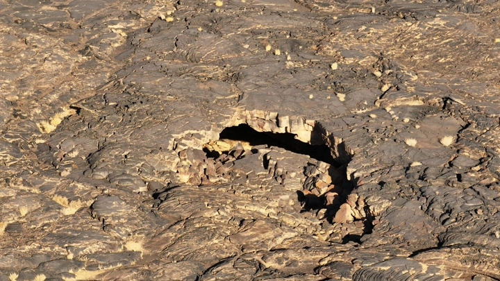 كهف بركاني في تضاريس صخرية، لقطة جوية.