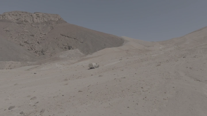 سيارة تسير في صحراء جبلية في السعودية، لقطة جوية.