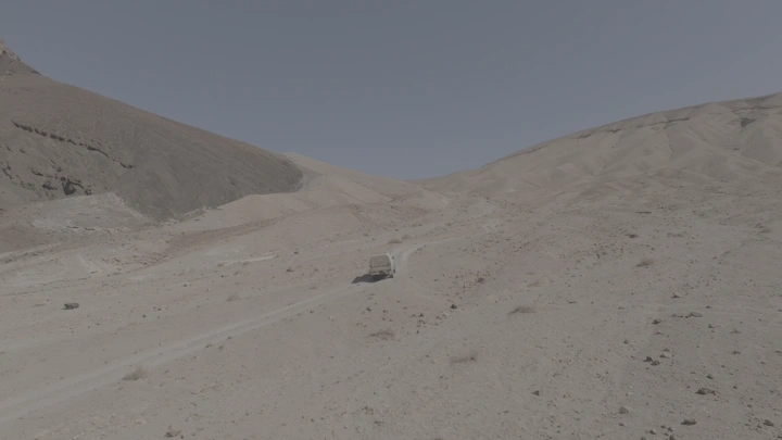 سيارة في صحراء جبلية تحت السماء الزرقاء، لقطة جوية.