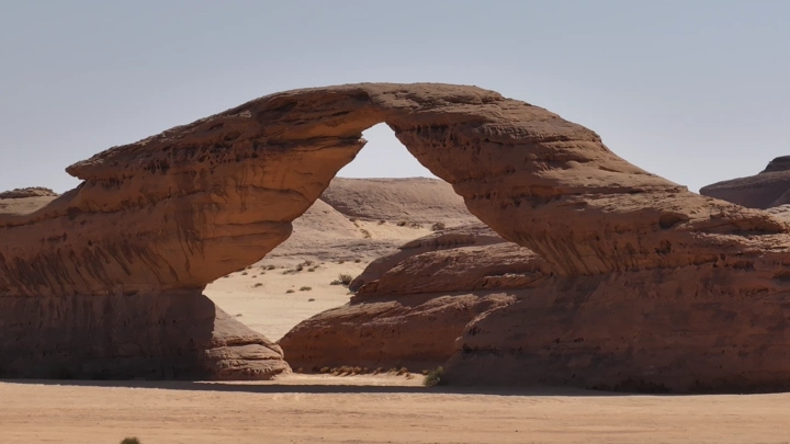 قوس صخري في العلا تحت السماء الصافية، لقطة نهارية.