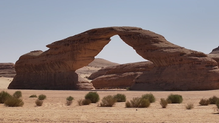 قوس صخري في العلا تحت سماء صافية، لقطة نهارية.