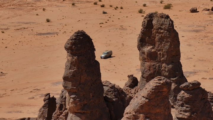 تكوينات صخرية في صحراء العلا مع سيارة، لقطة جوية.