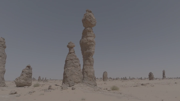 تكوينات صخرية في الصحراء تحت سماء زرقاء، لقطة واسعة.