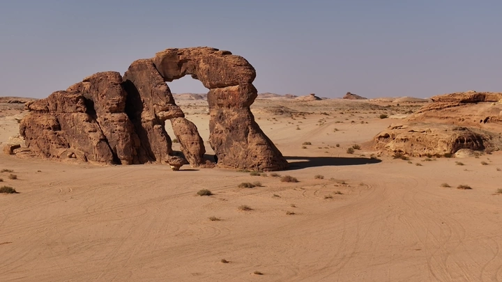 قوس صخري في صحراء نهارًا، لقطة بانورامية.