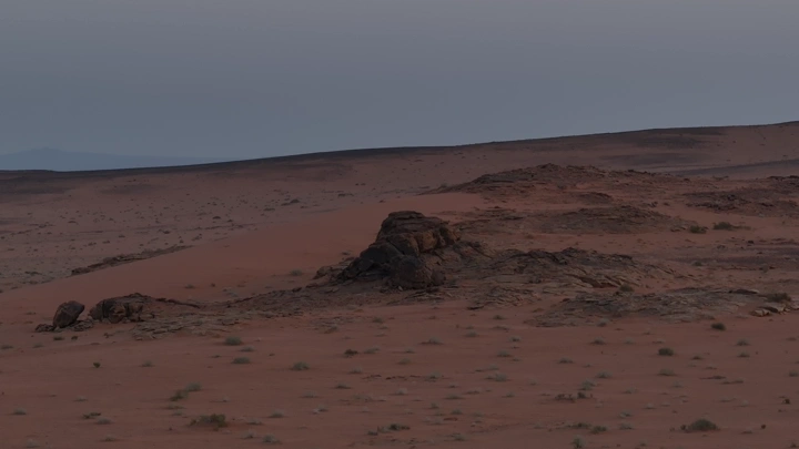 صحراء وجبال في الأفق عند الغروب، لقطة واسعة.