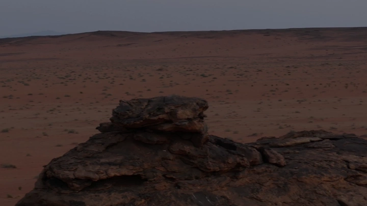 تكوين صخري في صحراء واسعة عند الغروب، لقطة علوية.