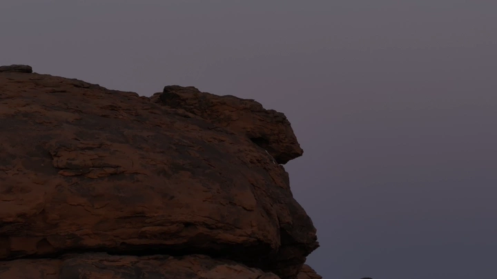 صخرة كبيرة في الصحراء عند الغسق، لقطة من الأرض.