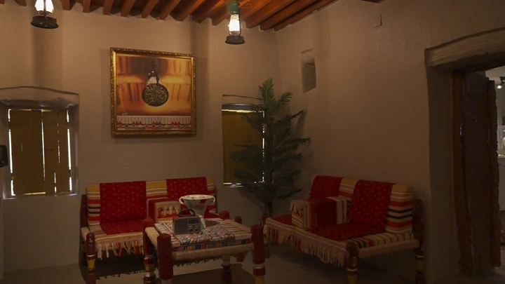 غرفة جلوس تقليدية بديكور عربي، إضاءة خافتة، زاوية واسعة.