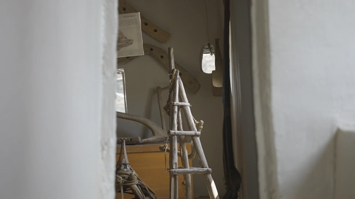 سلم خشبي صغير داخل غرفة ضيقة، لقطة داخلية.