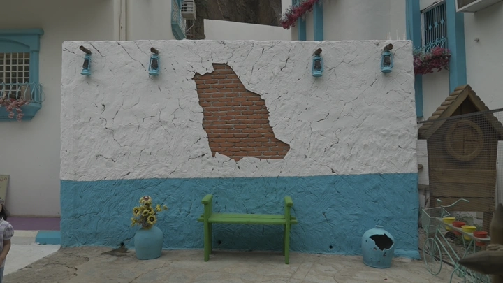 جدار حجري مع مقعد أخضر في رجال المع، لقطة نهارية.