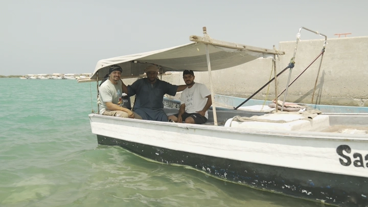 صيادون يجلسون في قارب صيد صغير في البحر، لقطة نهارية.