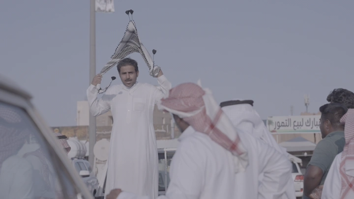 رجل يرتدي الزي التقليدي في سوق التمور بحائل، لقطة نهارية.