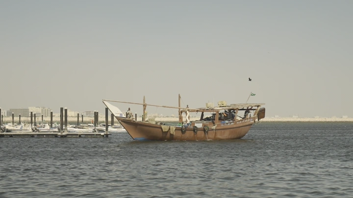 قارب خشبي في المرسى تحت السماء الصافية، لقطة نهارية.