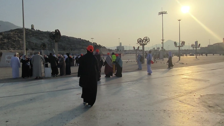 Visitors at Mount Arafat in Mecca at sunset with pigeons flying, ground shot.
