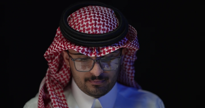 رجل سعودي يرتدي نظارات يعمل، لقطة جانبية.