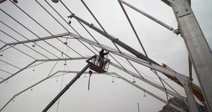 عامل على رافعة في موقع إنشائي، لقطة من الأسفل.