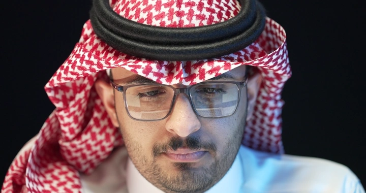 رجل سعودي يرتدي نظارات يعمل، لقطة جانبية.