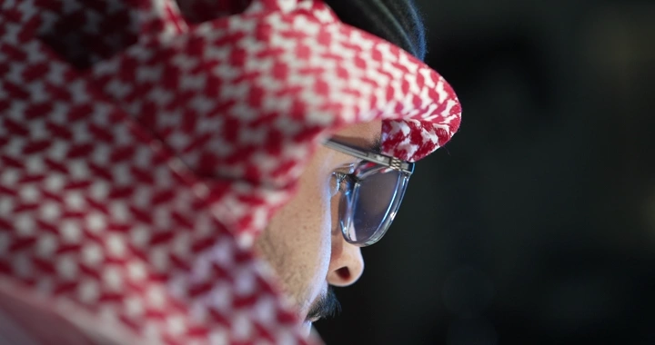 رجل سعودي يرتدي نظارات يعمل، لقطة جانبية.