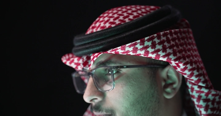 رجل يرتدي نظارات وعقال، لقطة جانبية، إضاءة خافتة.