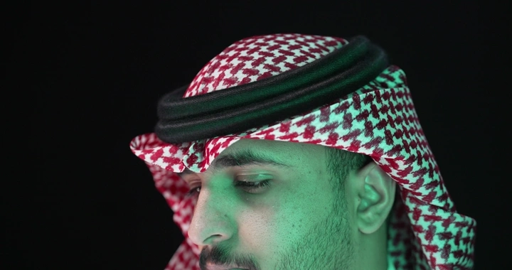 رجل يرتدي شماغًا سعوديًا، لقطة مقربة بإضاءة خضراء.