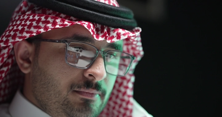 رجل سعودي يرتدي نظارات يعمل في مكتب، لقطة قريبة.