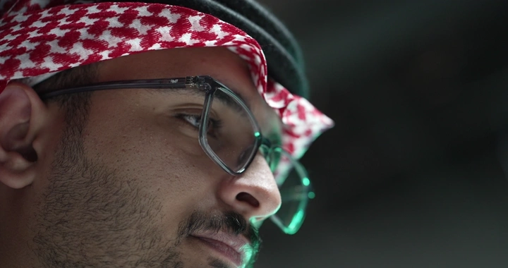 رجل سعودي يرتدي نظارات يعمل، لقطة جانبية.