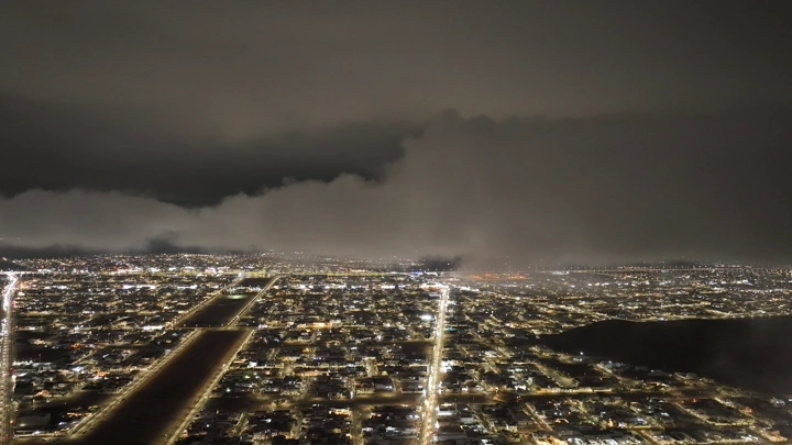 Hail city at night under cloudy skies, aerial shot.